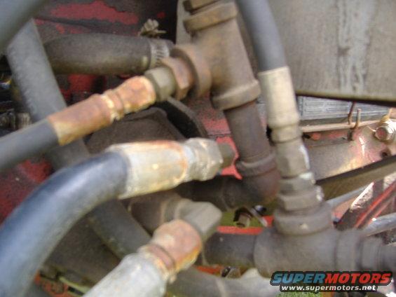 Close-up of hydraulic hoses and metal fittings, some showing rust