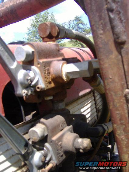 Close-up of hydraulic pump and hoses on a red tractor