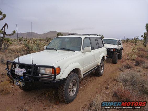 White Toyota Land Cruiser (1990-1997) and another SUV on a desert trail