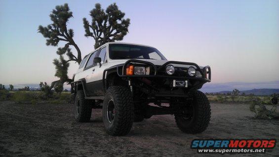 Modified 1985 Toyota 4Runner with aftermarket bumper and large tires parked in a desert landscape