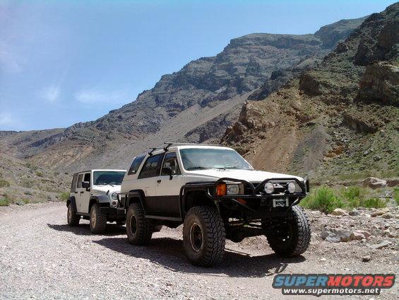 White and black 1985 Toyota 4Runner with off-road modifications on a dirt road