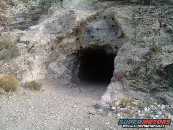 Mine entrance in rocky terrain with graffiti on the right side