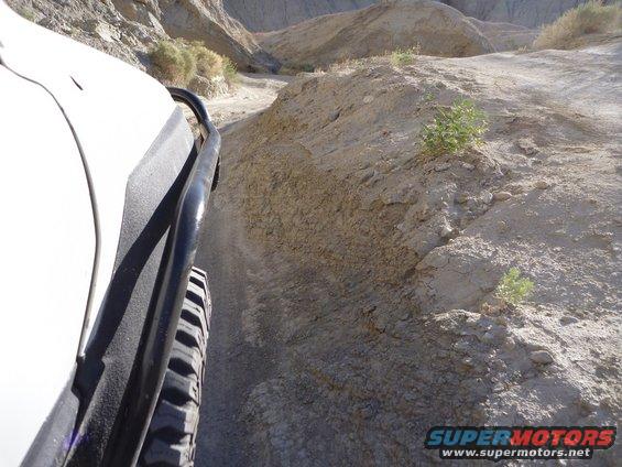 View from inside a vehicle driving on a dirt trail in a desert canyon