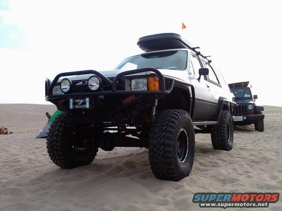 1985 Toyota 4Runner with off-road tires and roof box on sand
