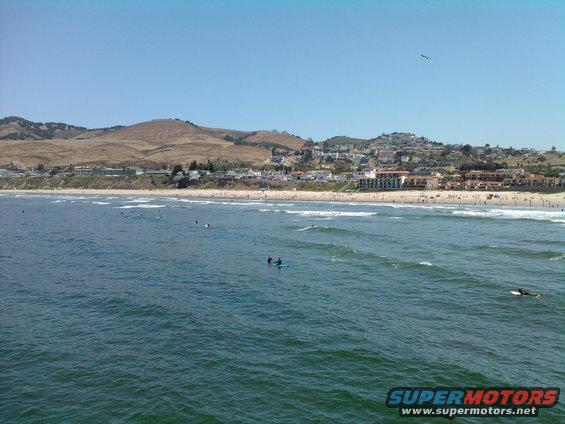 Ocean waves with surfers and a coastal town in the background