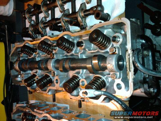 Engine cylinder head assembly showing camshaft, rocker arms, valves, and springs
