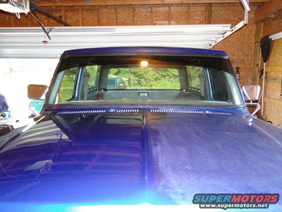 1978 Ford Bronco interior showing dashboard and rear window view; blue hood in foreground