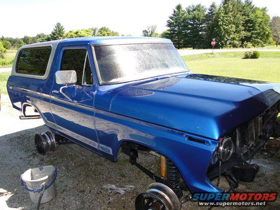 Blue SUV body, missing front end parts and wheels, parked outside