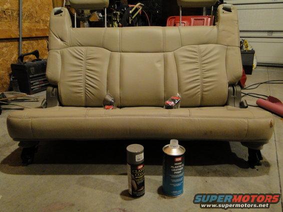 Car seat with two seat belts and two cans of cleaning product on concrete floor