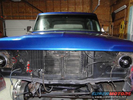 Front of a blue pickup truck with the grille and radiator exposed, showing the engine bay