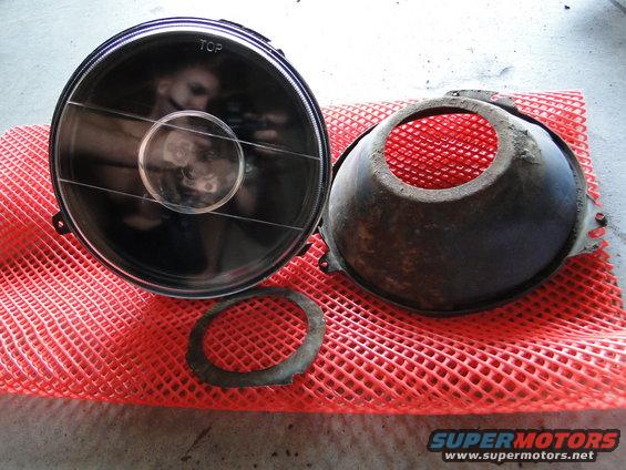 Headlight assembly and housing on red mesh mat. Text 'TOP' visible