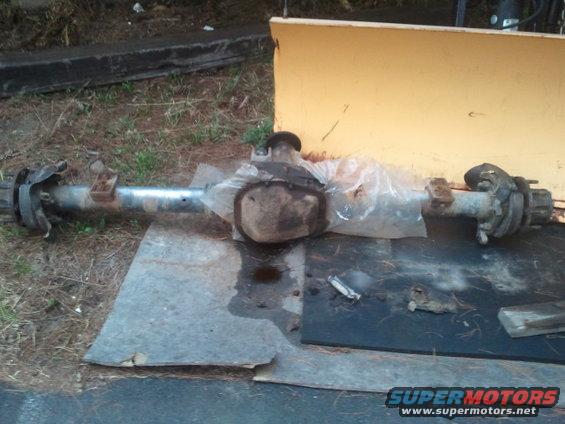 Rear axle assembly with brake drums, covered in plastic, on a metal sheet