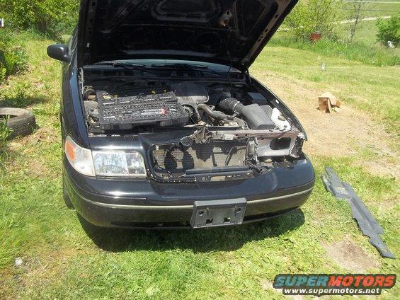 Front view of a black 2004 Ford Crown Victoria with the hood open, showing the engine and a toolbox