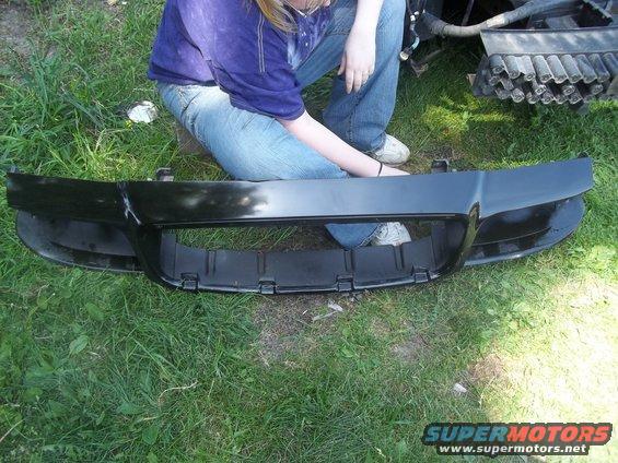 Black car bumper with a large central grille opening, lying on grass