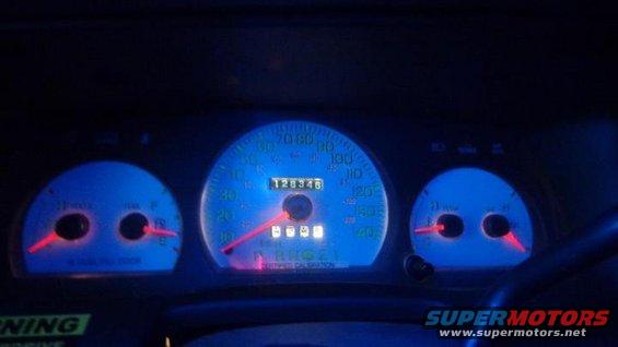 Car dashboard with blue illuminated gauges. Speedometer shows 128346 miles