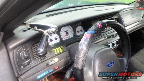 2003 Ford Crown Victoria interior showing dashboard, steering wheel with butterfly cover, and aftermarket shifter