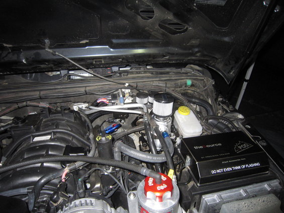 Engine bay with custom oil catch cans and a black box labeled "the source POD"