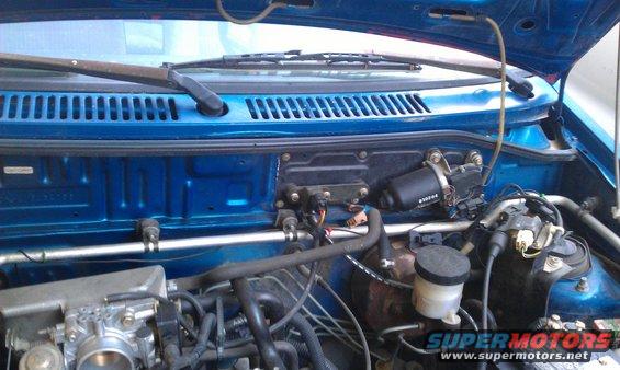 Blue car's engine bay with wiper motor and brake fluid reservoir visible