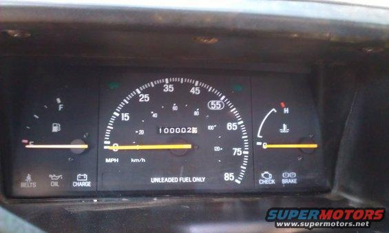 Speedometer reads 100,000 miles, fuel gauge is low, temperature gauge is normal
