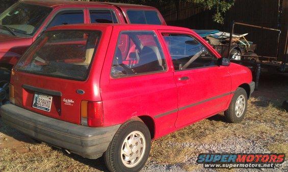 red 1991 Ford Festiva parked next to a red truck