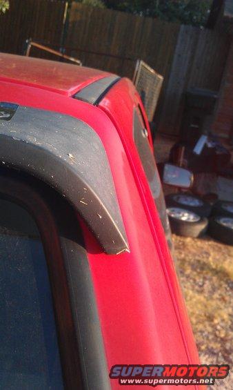 Red vehicle roof trim with black plastic accent. Some dirt visible