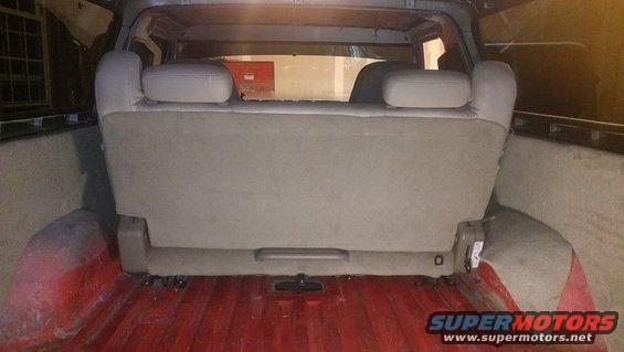 Rear interior view of a vehicle showing a folded-down seat and red-painted cargo bed