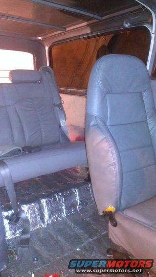Interior view of vehicle seats and floor. Some insulation is visible on the floor
