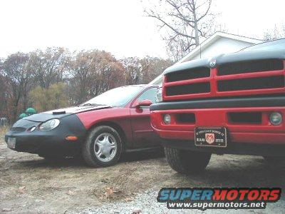Red 1997 Ford Taurus with a car bra parked next to a red Dodge Ram truck