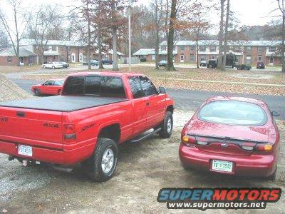 Red sedan from rear, license plate W V 1547, next to a red pickup truck