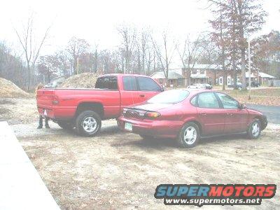 Red 1997 Ford Taurus parked next to a red pickup truck