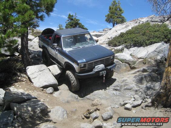 Blue and silver SUV navigating a rocky trail with a spare tire mounted in the back
