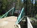 1986 Ford Bronco - A man stands next to a brown Ford Bronco on a wooden bridge in a forest.