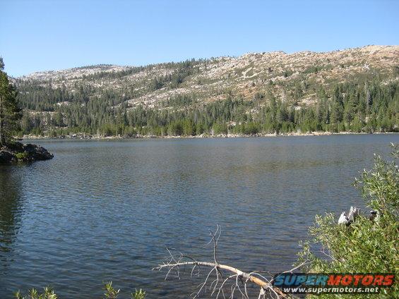 Lake and forested mountains under a clear blue sky