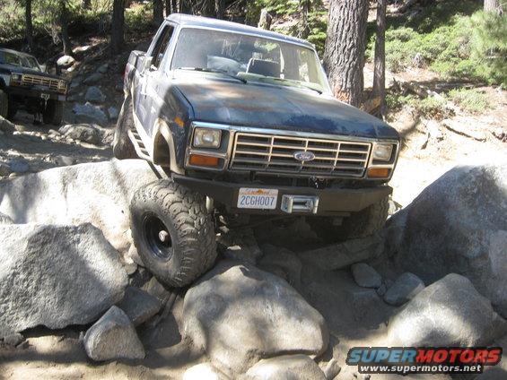 Blue Ford truck navigating rocky terrain, front view