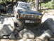 1986 Ford Bronco - A blue Ford truck navigates a challenging rocky trail, with another similar vehicle visible in the background.