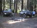 1986 Ford Bronco - Two lifted Ford pickup trucks are parked in a forest with two men standing next to them.