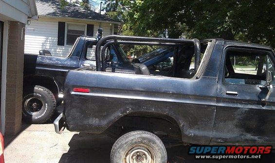 Two Ford Broncos parked next to each other, one with a roll cage