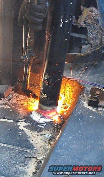 Cutting a metal tube with a torch, sparks flying. Supermotors.net logo visible