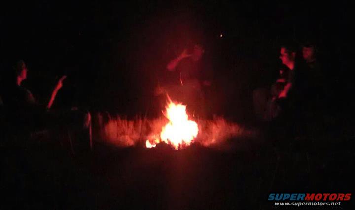 people sitting around a campfire at night
