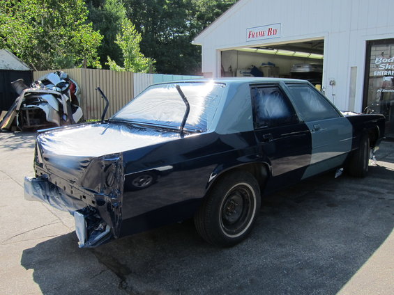 1991 Ford Crown Victoria LTD with plastic sheeting and masking tape, parked outside a body shop