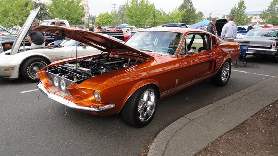 Orange 1967 Ford Mustang GT500 with hood open, parked next to a white car