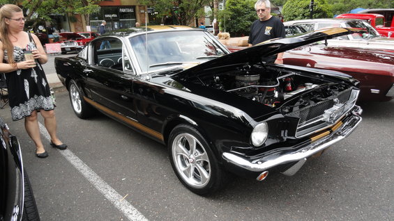 Black 1965 Ford Mustang fastback with gold stripe and hood open