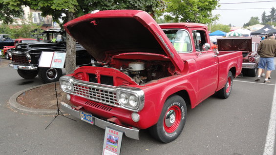 Red 1958 Ford F-100 pickup truck, hood open, showing engine. Front 3/4 view