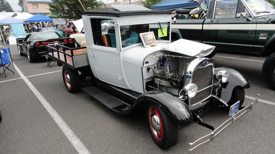1929 Ford Model A pickup truck with flatbed, parked next to a black Chevrolet Corvette