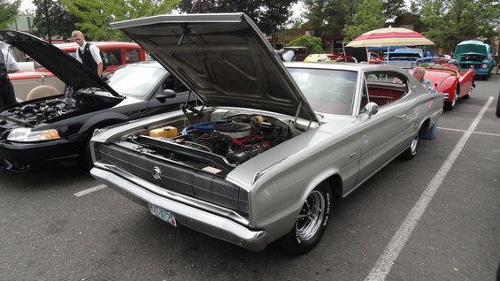 Silver 1966 Dodge Charger with hood open, parked next to a black Ford Mustang