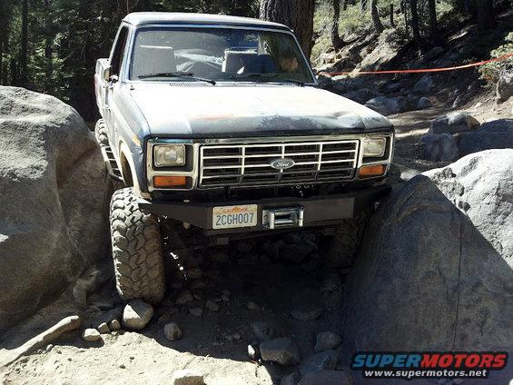 Ford truck with large tires navigating rocks on a trail. License plate reads 2CGH007
