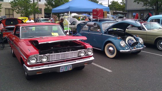 Red 1964 Ford Fairlane with hood open, parked next to a blue Volkswagen Beetle