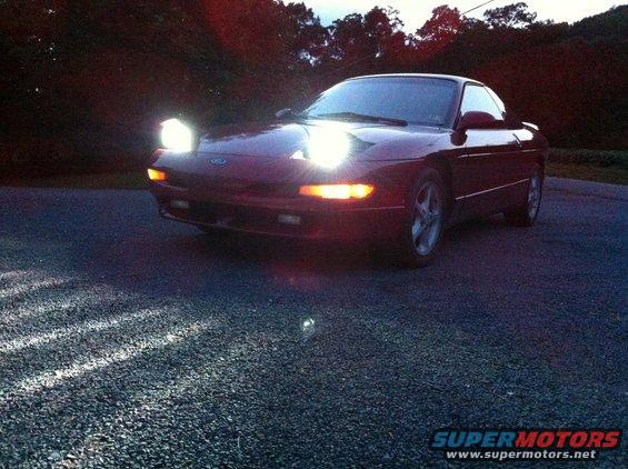 Red 1994 Ford Probe with headlights on, front 3/4 view