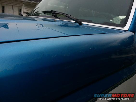 Blue SUV hood with peeling paint, close-up angle showing windshield wiper
