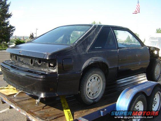 Black 1987 Ford Mustang coupe, rear 3/4 view, missing rear bumper and headlights